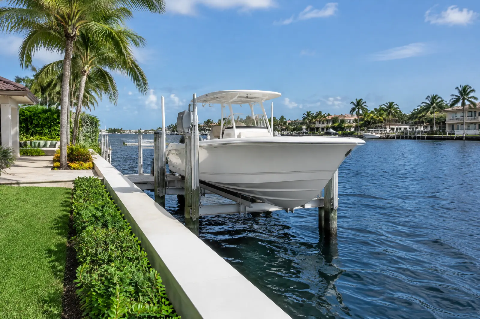 Boat on a seawall-mounted elevator lift at a waterfront home with the Intracoastal beyond