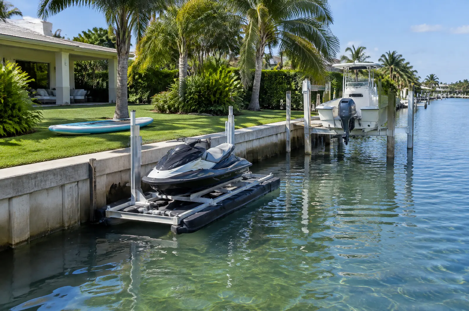 Floating jet ski lift and small boat lift set parallel to a seawall on a residential canal