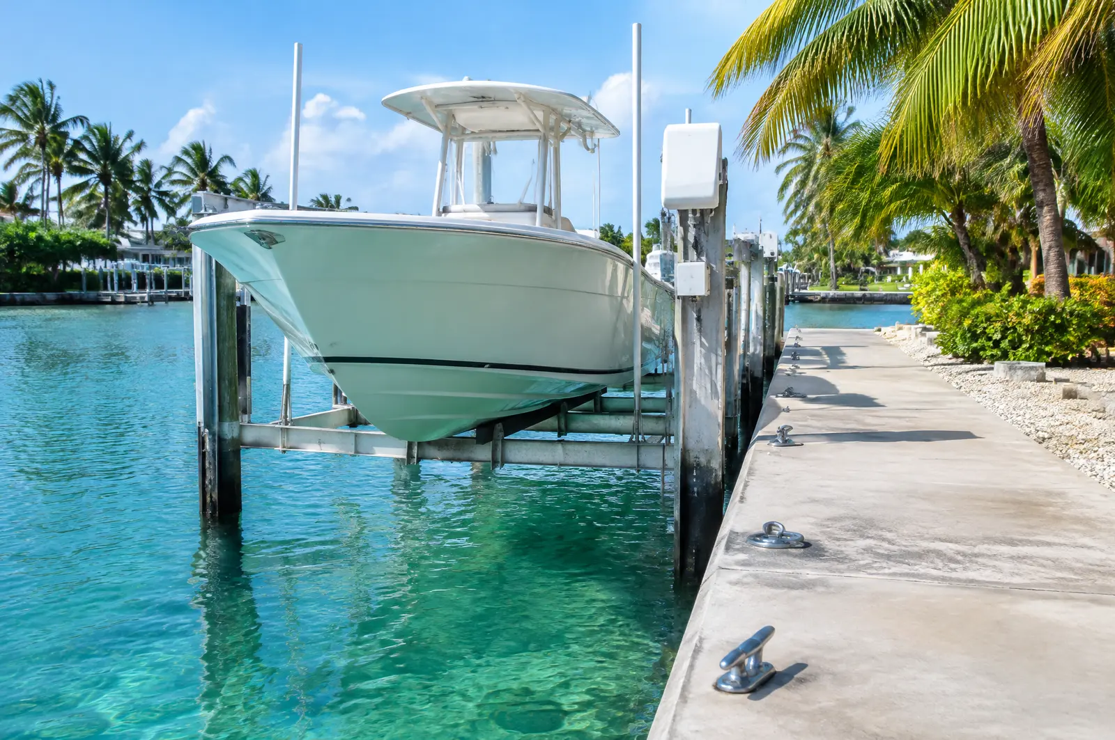Boat on an elevator lift on a clear Keys canal with cleats and tie-down rings on the dock