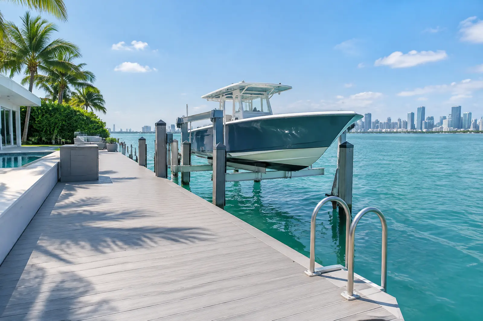 Modern private dock and boat lift at a bayfront home with the city skyline faint across the water