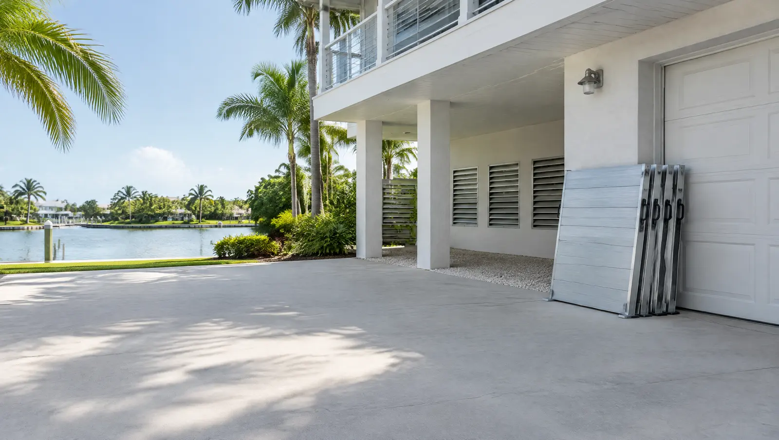 Raised home with flood vents in the enclosure wall and removable flood barrier panels stacked by the garage