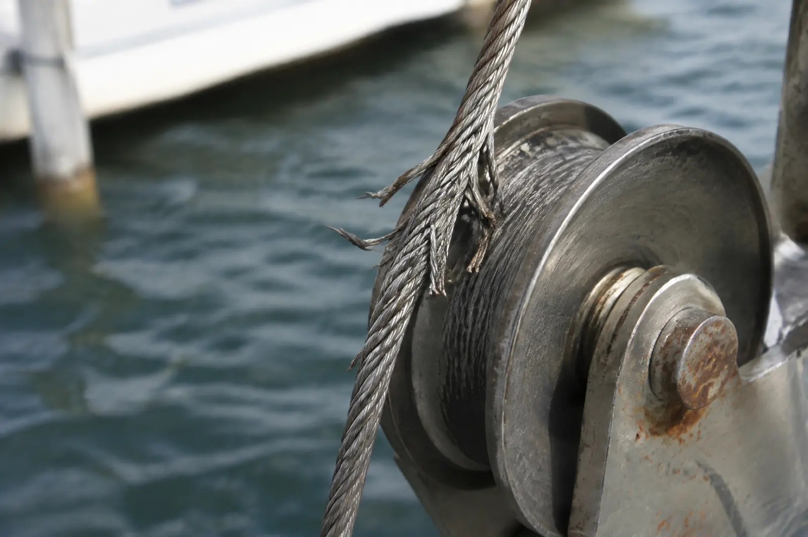 Stainless boat lift cable with broken strands where it runs over a pulley