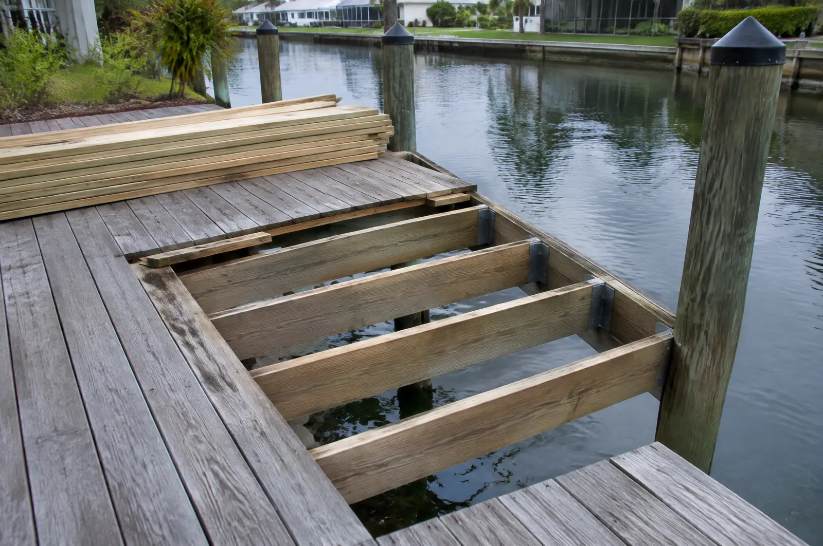Dock with old boards removed to expose joists and new boards stacked ready
