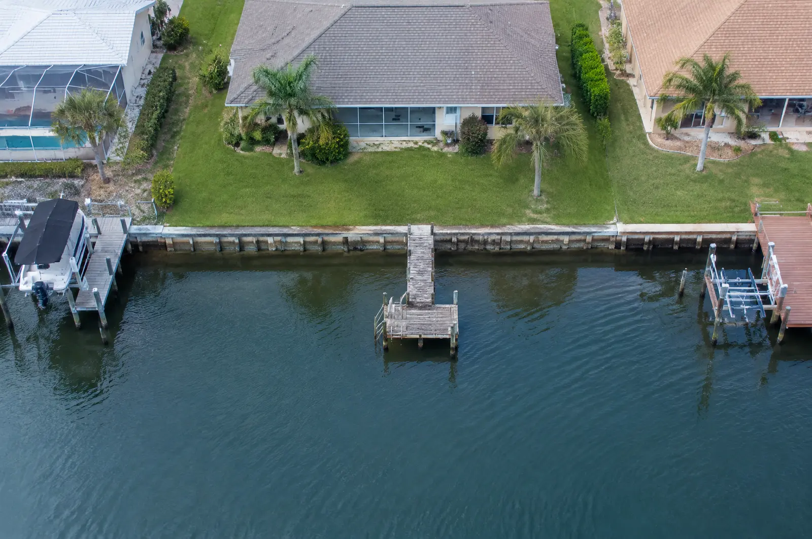 Overhead view of a canal-front lot with a seawall and small dock, showing the canal width and neighbouring docks
