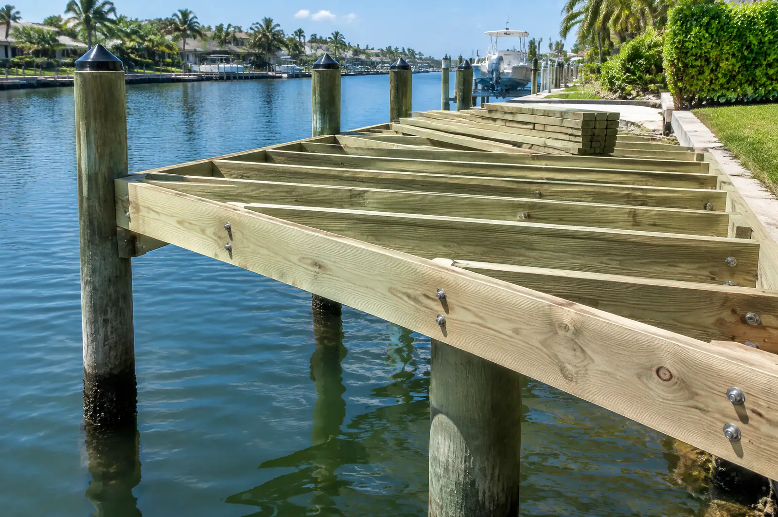 New dock framing of pressure-treated joists and stringers bolted to pilings over a canal