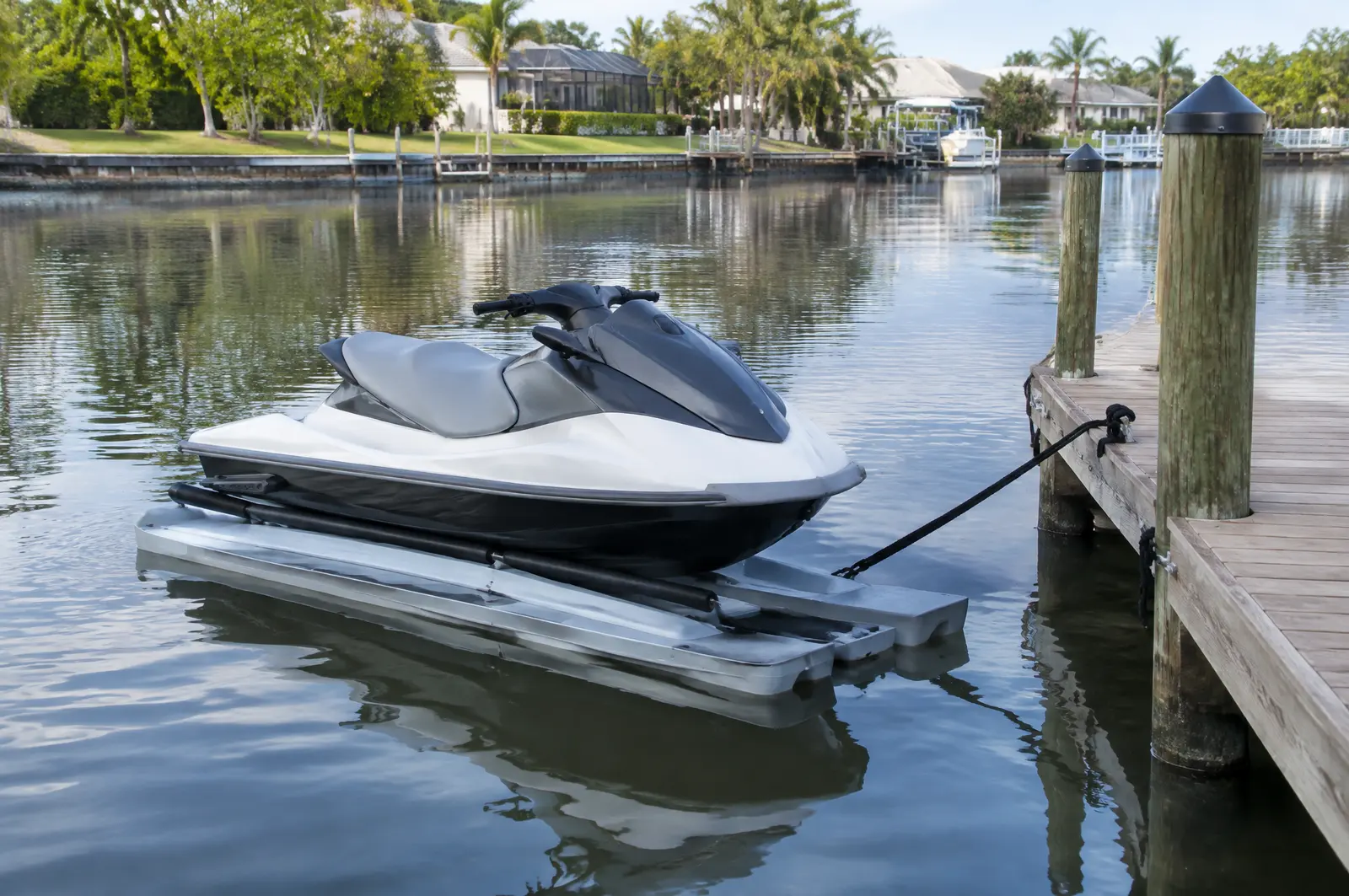 Plain jet ski on a low floating drive-on lift tied to a residential dock