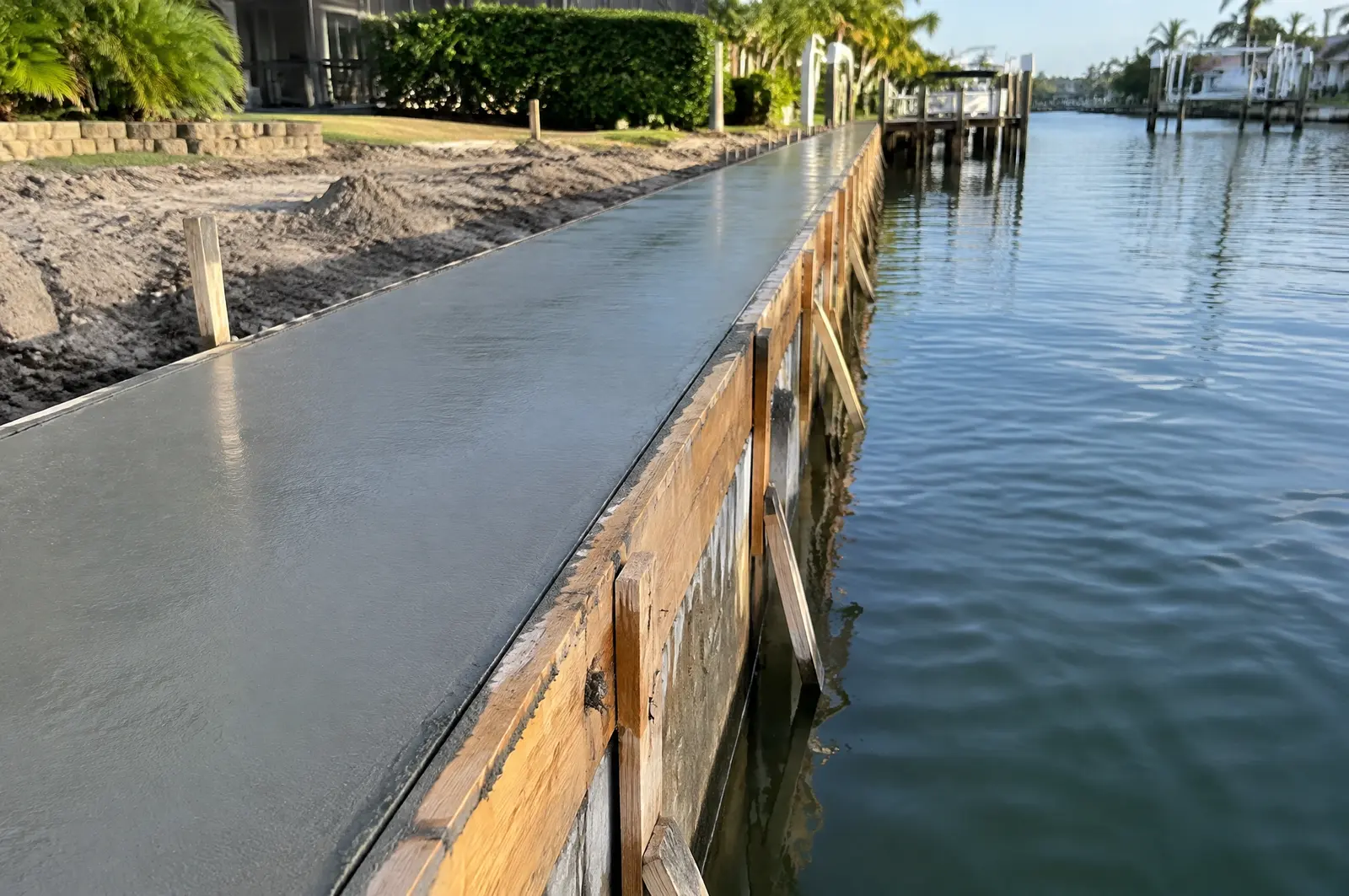 Freshly poured smooth concrete seawall cap with timber formwork along the edge